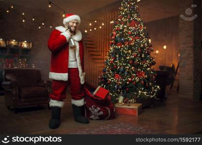 Bad drunk Santa claus brings gifts, nasty party. Unhealthy lifestyle, bearded man in holiday costume, new year and alcoholism. Bad drunk Santa claus brings gifts, nasty party