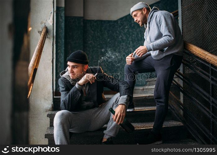 Bad guys waiting for victim on the stairs and smoking. Street robber, criminal danger. Crime concept