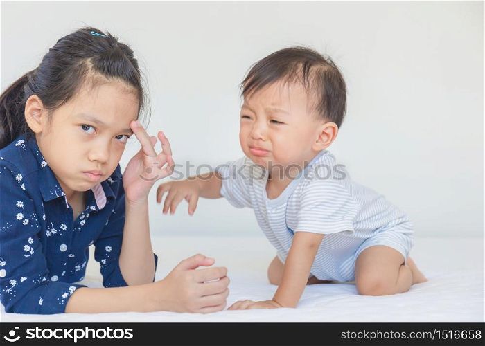 Bad mood sister and crying baby brother, kids playing on the bed