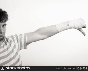 Bad news and information. Medicine aspects. Sad unhappy male with bandaged hand showing thumb down sign symbol.. Sad man showing thumb down by bandaged hand.