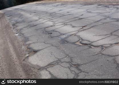 Bad road with cracks and the part of the ground and grass