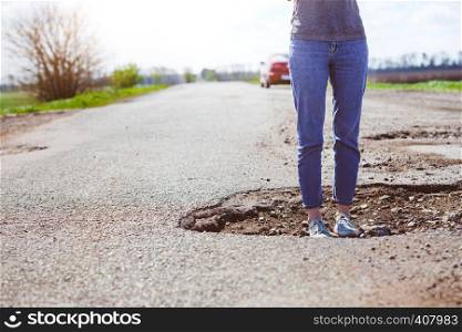 bad roads - a girl stands in a hole in the road