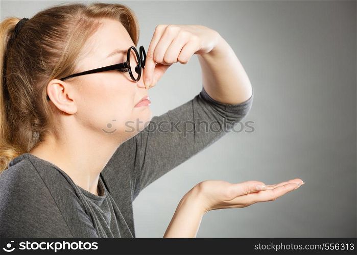 Bad smell concept. Young woman feels disgust pinches her nose with fingers because of odor stench unpleasant stink. Facial reaction.. Girl pinches her nose because of stench stink.