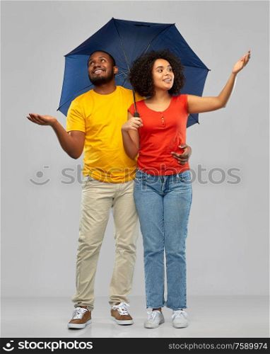 bad weather, overcast and protection concept - happy smiling african american couple in white t-shirts with umbrella over grey background. smiling african american couple with umbrella