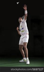 Badminton player preparing to serve over black background