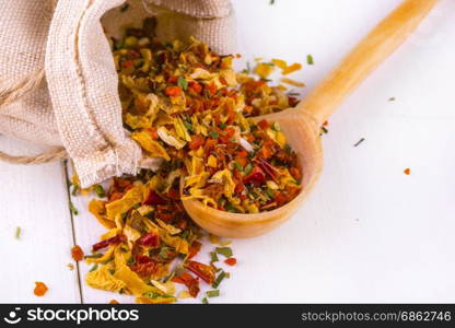 Bag of sackcloth with dried spices and a wooden spoon on a white kitchen table