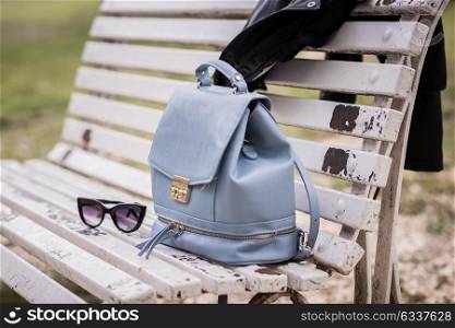 Bag, sunglasses and leather jacket on a bench of a urban park