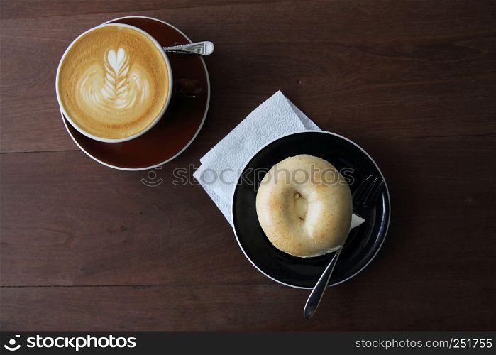 bagel with hot coffee on wood background