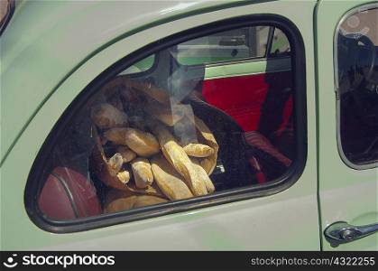 Bags of baguettes in back seat of vintage car, Brignogan, France