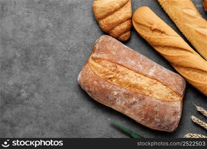 Baguette, croissant and ciabatta. Fresh baked wheat bread lies on a gray table. Various types of freshly baked bread. Bakery top view, local bakery concept