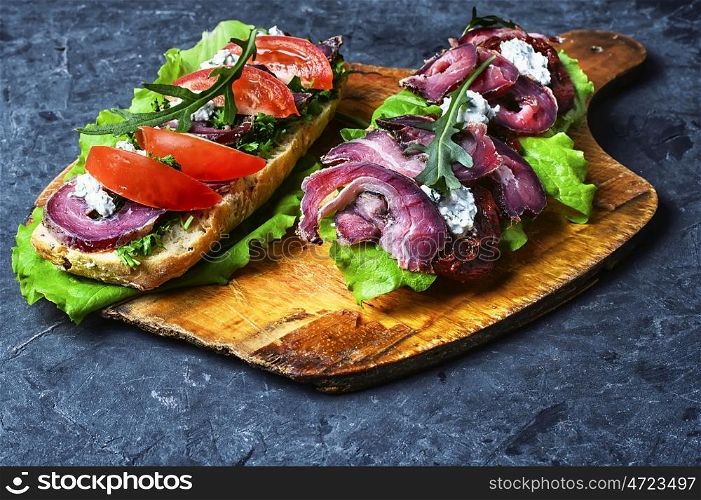 Baguette with bacon and vegetables. sandwiches with bacon and vegetables on blue slate background