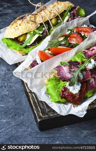 Baguette with bacon and vegetables. sandwiches with bacon and vegetables on blue slate background
