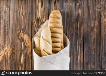 baguettes wrapped paper wooden background. High resolution photo. baguettes wrapped paper wooden background. High quality photo