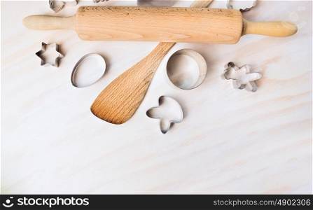 Bake tolls and easter cookie cutters on white wooden background, top view,place for text