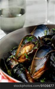 Baked blue mussels in spicy with lemon in a black cast-iron pot