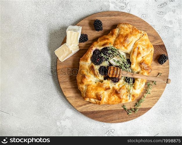 Baked brie cheese and blackberry open pie galette with thyme and honey. Homemade puff pastry baking, sweet-savory taste, gourmet appetizer.