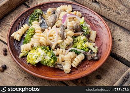 Baked broccoli and pasta with mushrooms.Vegetarian vegetable pasta wooden table.. Pasta with vegetables
