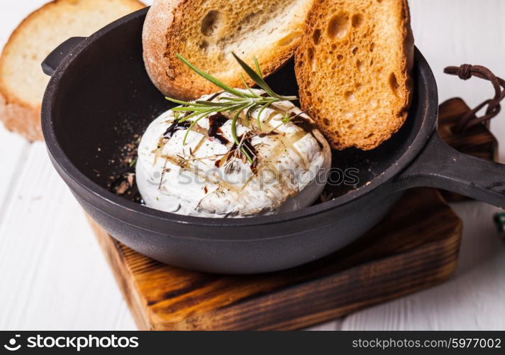 Baked camembert with herbs and spices on the pan. Baked camembert