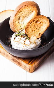 Baked camembert with herbs and spices on the pan. Baked camembert