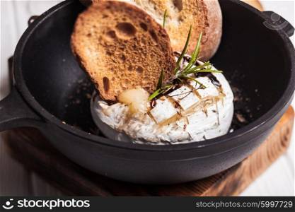 Baked camembert with herbs and spices on the pan. The Baked camembert