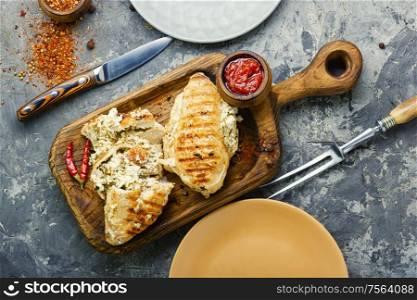 Baked chicken breast stuffed with cheese on kitchen board. Chicken breast with feta cheese