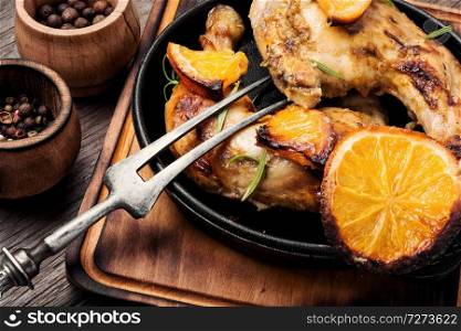 Baked chicken drumsticks with orange sauce in skillet. Roast chicken with orange