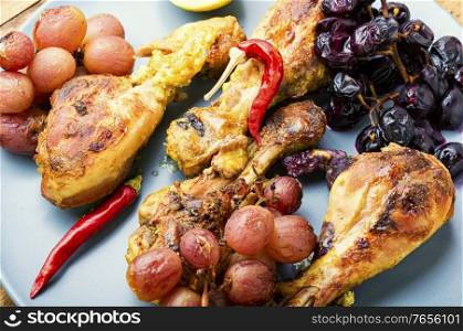 Baked chicken legs with grapes.Roasted chicken legs on plate. Baked chicken drumsticks