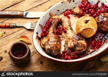 Baked chicken meat with berries on wooden background.Chicken drumsticks roasted with viburnum. Chicken meat with viburnum,wooden background