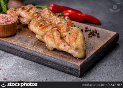 Baked chicken wings served with different sauces and lemon. Gray background. Baked chicken wings with sesame seeds and sauce on a wooden cutting board