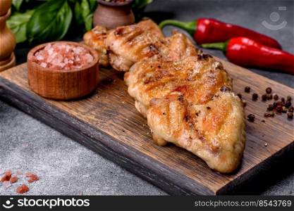 Baked chicken wings served with different sauces and lemon. Gray background. Baked chicken wings with sesame seeds and sauce on a wooden cutting board