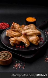 Baked chicken wings with salt, spices and herbs on a dark concrete background