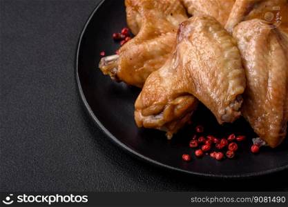 Baked chicken wings with salt, spices and herbs on a dark concrete background