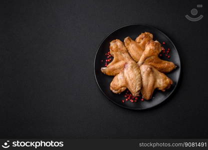 Baked chicken wings with salt, spices and herbs on a dark concrete background