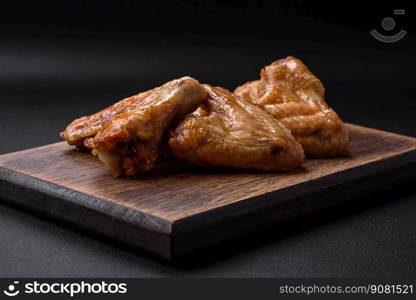 Baked chicken wings with salt, spices and herbs on a dark concrete background