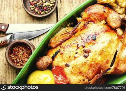 Baked chicken with apples on old wooden table.Fried chicken with apples.Tasty aromatic rotisserie chicken. Baked chicken with apples.