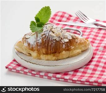 Baked croissant sprinkled with sugar on wooden board, red napkin