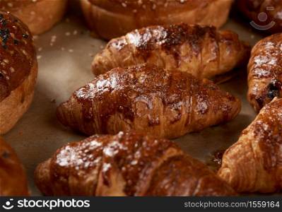 baked croissants in a baking sheet on brown parchment paper, delicious and appetizing pastries
