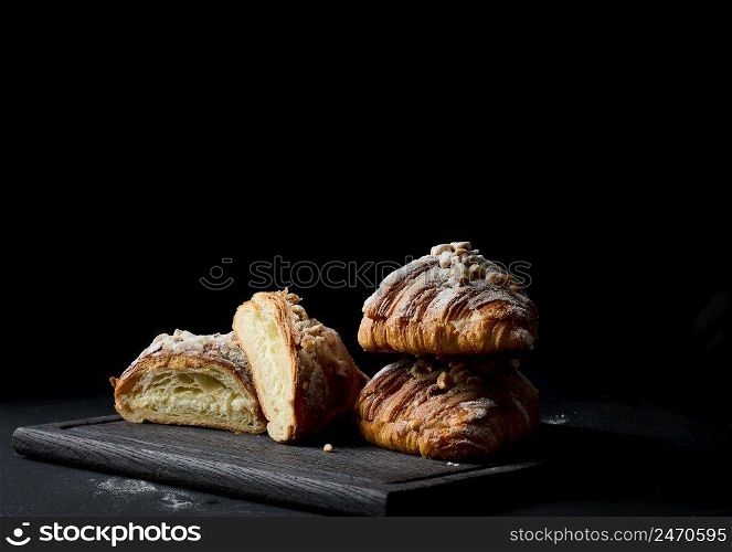 baked croissants on a black wooden board sprinkled with powdered sugar 
