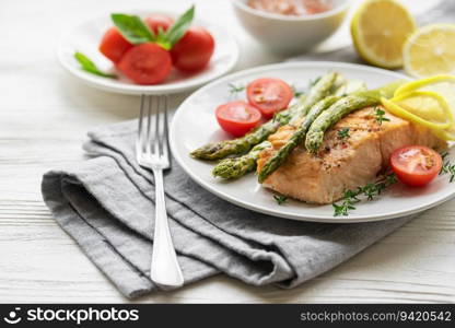 Baked Delicious salmon, green asparagus with vegetables on plate 