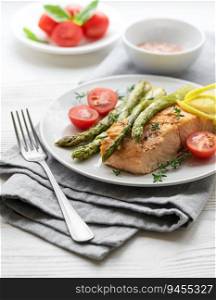 Baked Delicious salmon, green asparagus with vegetables on plate 