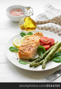 Baked Delicious salmon, green asparagus with vegetables on plate 