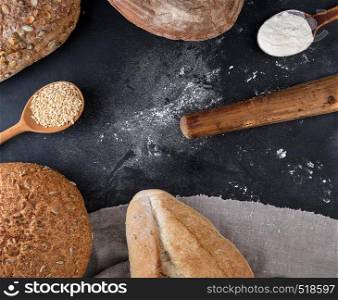 baked different loaves of bread on a black background, top view