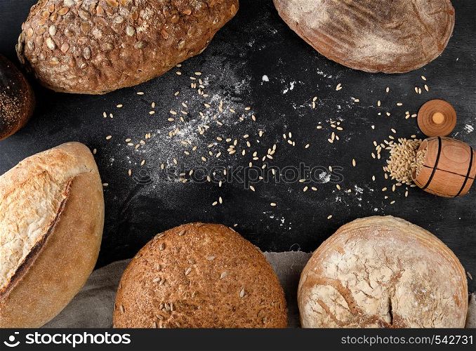 baked different loaves of bread on a black background, top view, copy space