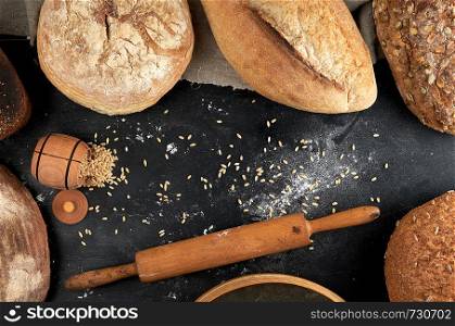 baked different loaves of bread on a black background, top view, copy space