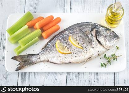 Baked dorada garnished with baby carrots and celery stalks