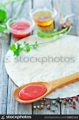 baked dough for pizza and sauce in the bowl