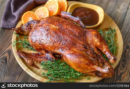 Baked duck with fresh thyme and oranges on wooden tray