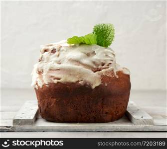 baked Easter cake with white lemon glaze on a white wooden board, traditional orthodox pastries