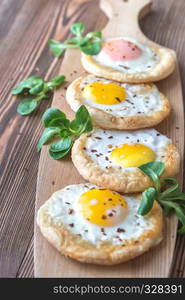 Baked eggs in puff pastry on the wooden board