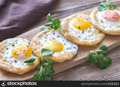 Baked eggs in puff pastry on the wooden board